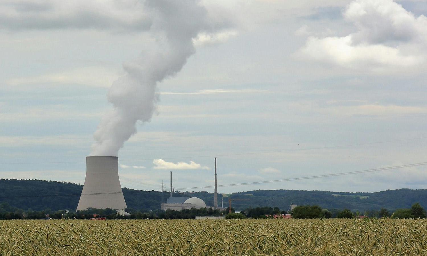 A wide shot of a field and nuclear reactor. 